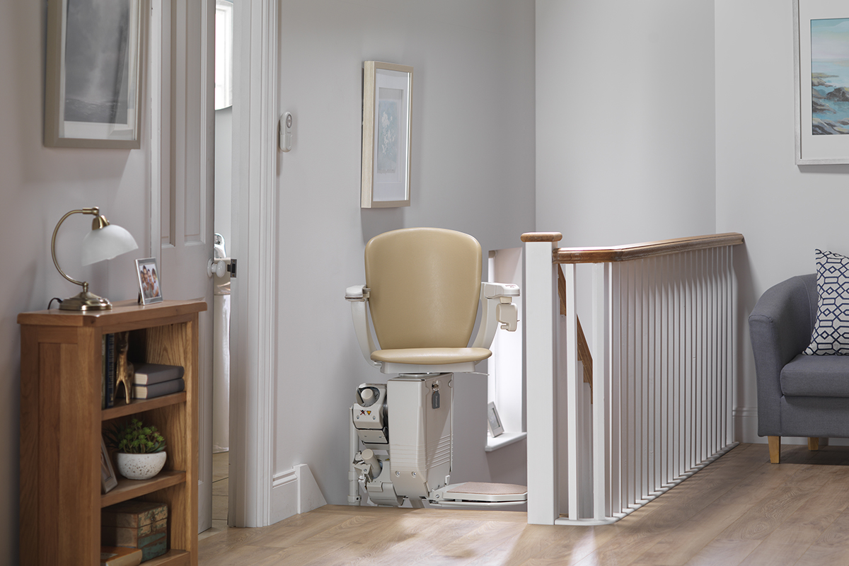 Woman on a Stannah stairlift at the top of the stairs on the first floor of the house